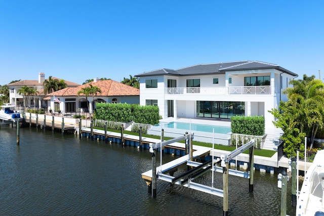 view of dock featuring an outdoor pool, a balcony, boat lift, and a water view