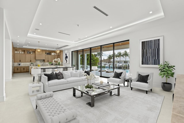 living room with visible vents, recessed lighting, baseboards, and a tray ceiling