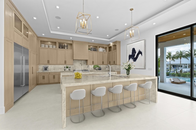 kitchen featuring light brown cabinets, a tray ceiling, stainless steel built in fridge, custom exhaust hood, and a sink