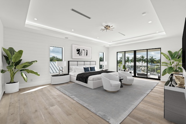 bedroom featuring a tray ceiling, access to outside, visible vents, and light wood finished floors