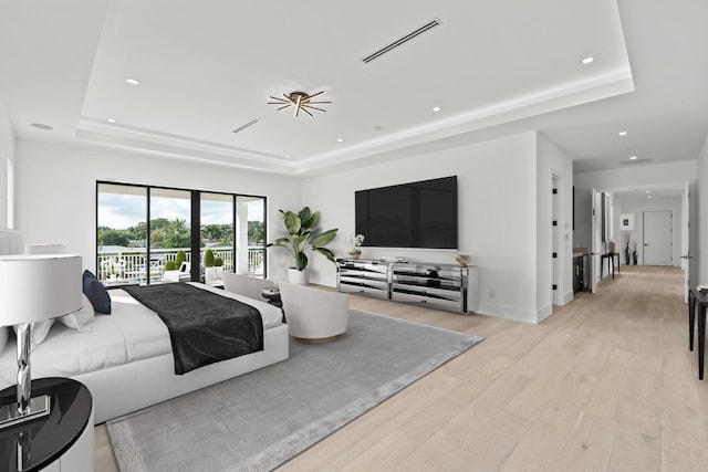 bedroom featuring a tray ceiling, visible vents, and light wood finished floors