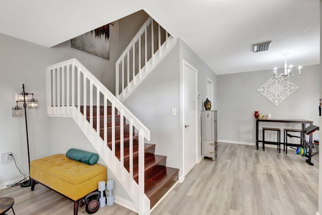 stairs featuring baseboards, visible vents, an inviting chandelier, and wood finished floors