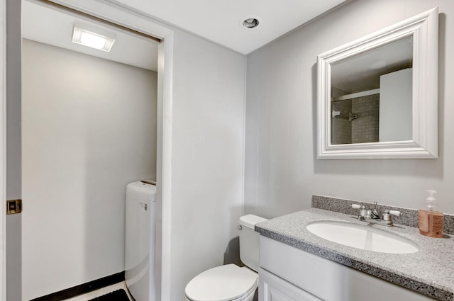 bathroom featuring toilet, tiled shower, and vanity