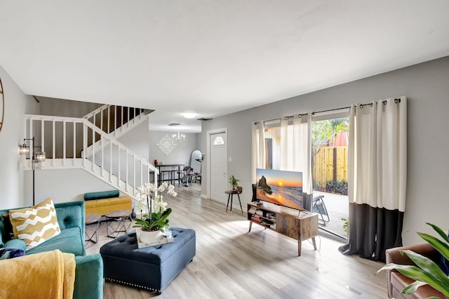 living area featuring an inviting chandelier, stairs, baseboards, and wood finished floors