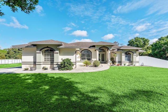 mediterranean / spanish house featuring a front yard, fence, and stucco siding