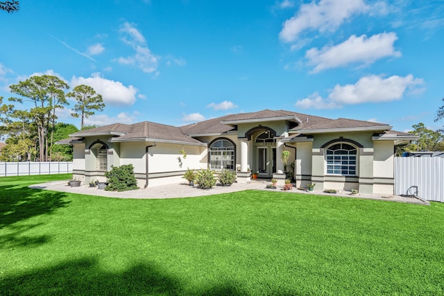 mediterranean / spanish-style home with a front yard, fence, and stucco siding