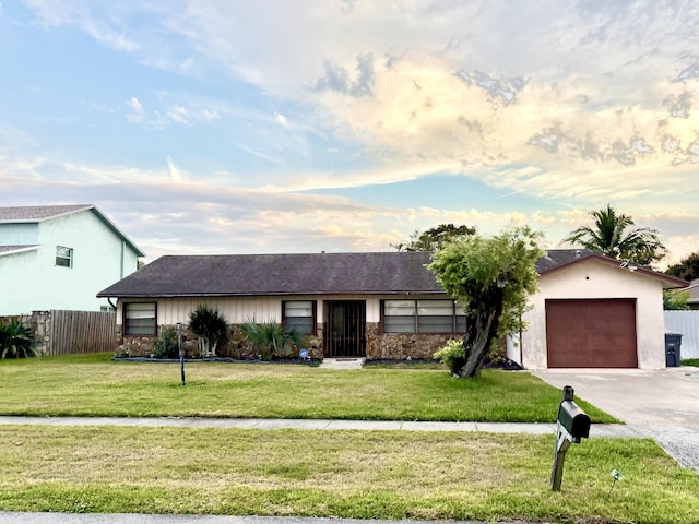 ranch-style home with a garage, driveway, fence, and a front lawn