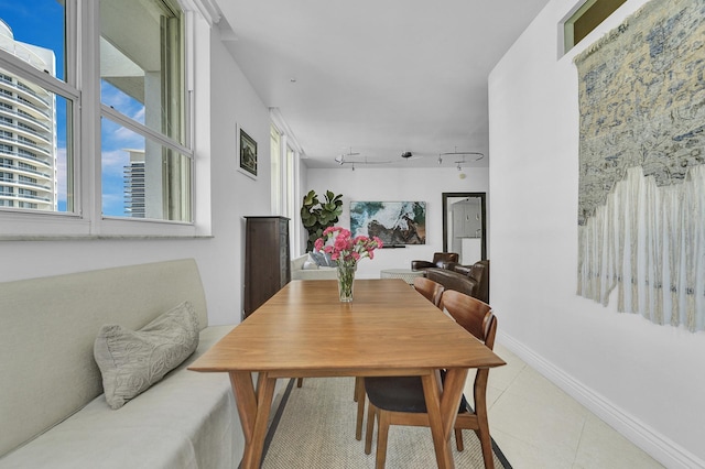 dining room with light tile patterned floors, track lighting, and baseboards