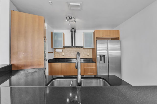 kitchen featuring dark countertops, visible vents, stainless steel fridge with ice dispenser, decorative backsplash, and wall chimney exhaust hood