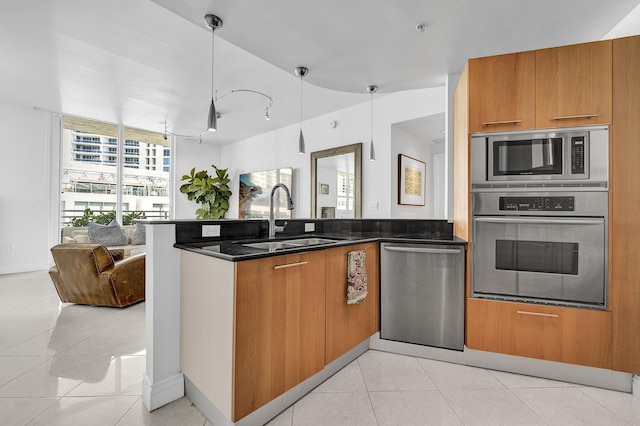 kitchen featuring a sink, open floor plan, stainless steel appliances, a peninsula, and light tile patterned floors