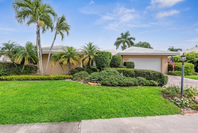 view of front of home with a front yard, decorative driveway, an attached garage, and stucco siding