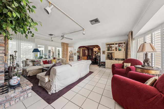 living room with a wealth of natural light, arched walkways, light tile patterned flooring, and visible vents