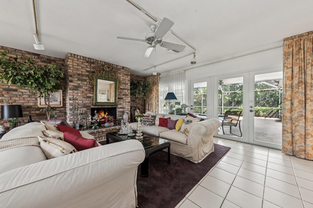 living room featuring light tile patterned floors, brick wall, a fireplace, french doors, and track lighting