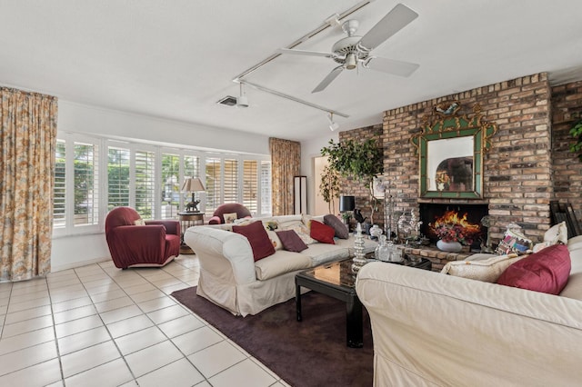 living area with a brick fireplace, ceiling fan, track lighting, and light tile patterned floors