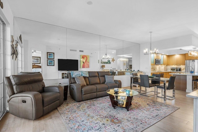 living area featuring light wood-style floors, visible vents, and a chandelier