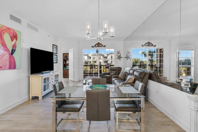 dining space with light wood-type flooring, an inviting chandelier, baseboards, and visible vents