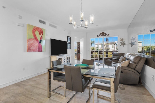 dining space featuring light wood-style floors, baseboards, visible vents, and a chandelier