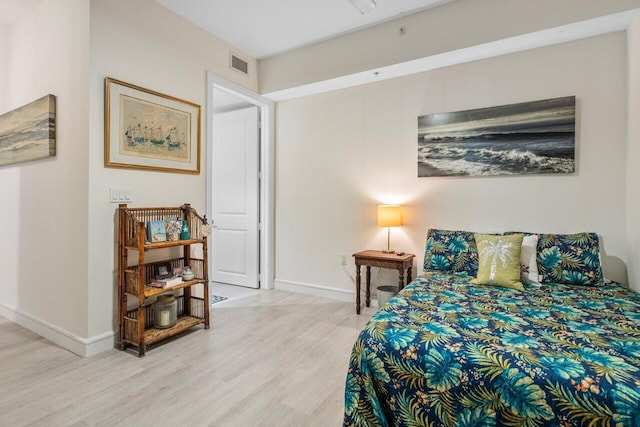 bedroom featuring light wood finished floors, visible vents, and baseboards