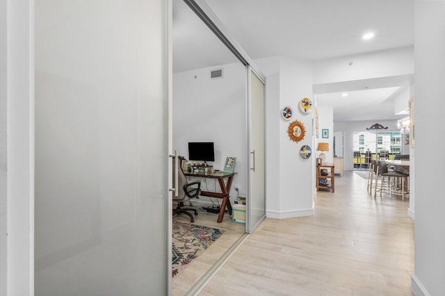 hallway featuring baseboards, visible vents, and wood finished floors