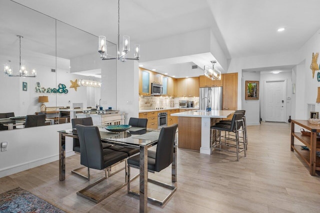 dining area featuring an inviting chandelier, light wood-style flooring, baseboards, and recessed lighting