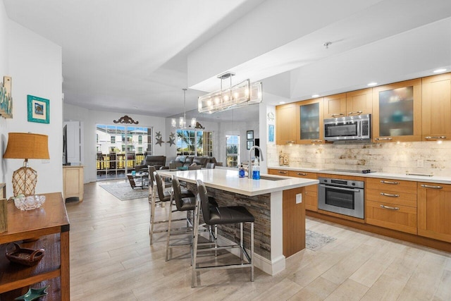 kitchen with stainless steel appliances, light countertops, a sink, and tasteful backsplash