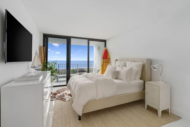 bedroom with a water view, access to exterior, expansive windows, and baseboards