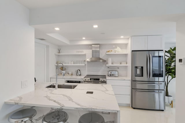 kitchen featuring wall chimney range hood, appliances with stainless steel finishes, open shelves, and a sink