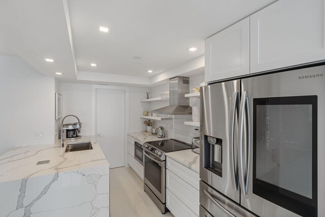 kitchen with stainless steel appliances, a sink, white cabinetry, wall chimney exhaust hood, and open shelves