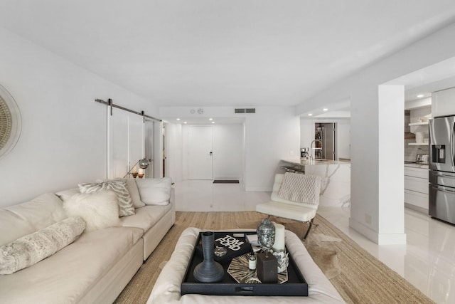 living room with light wood-style floors, a barn door, visible vents, and recessed lighting