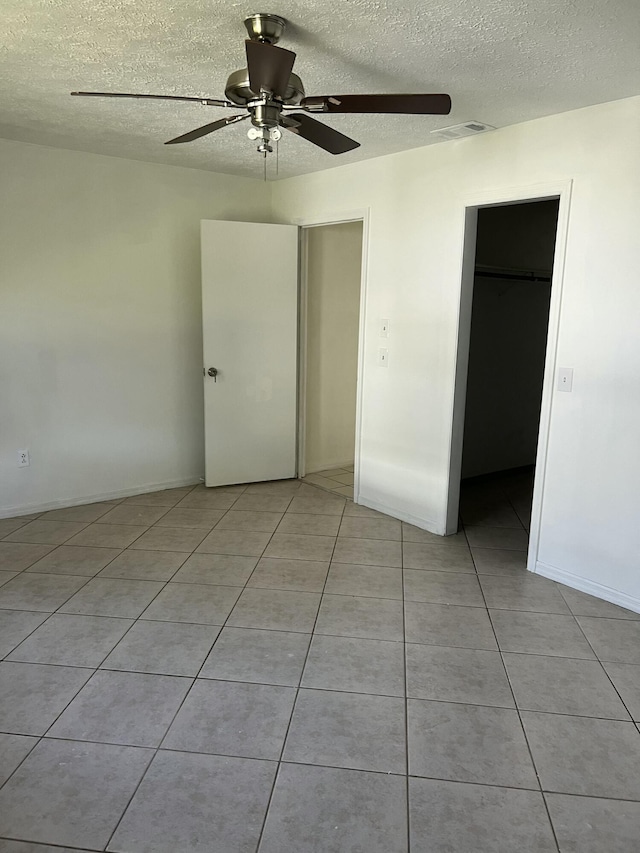 unfurnished bedroom with light tile patterned floors, visible vents, a ceiling fan, a textured ceiling, and a closet