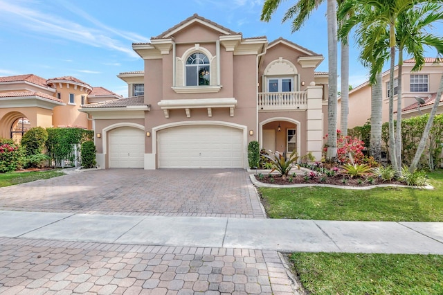 mediterranean / spanish home featuring a tiled roof, decorative driveway, a balcony, and stucco siding