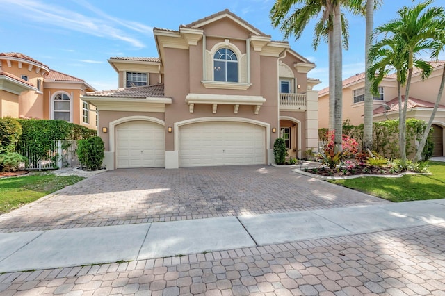 mediterranean / spanish-style house with decorative driveway, a tiled roof, and stucco siding