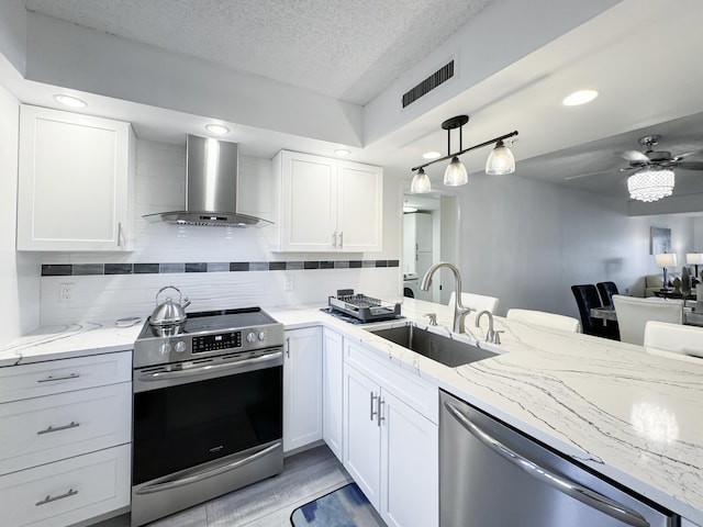 kitchen with visible vents, a sink, appliances with stainless steel finishes, wall chimney range hood, and decorative backsplash