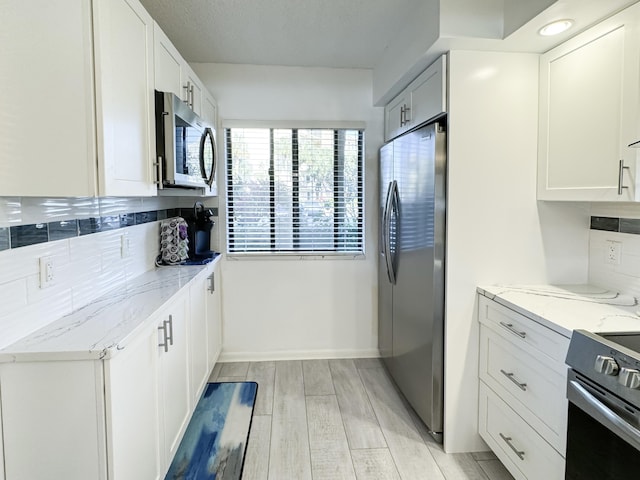 kitchen featuring light wood finished floors, light stone countertops, tasteful backsplash, and appliances with stainless steel finishes