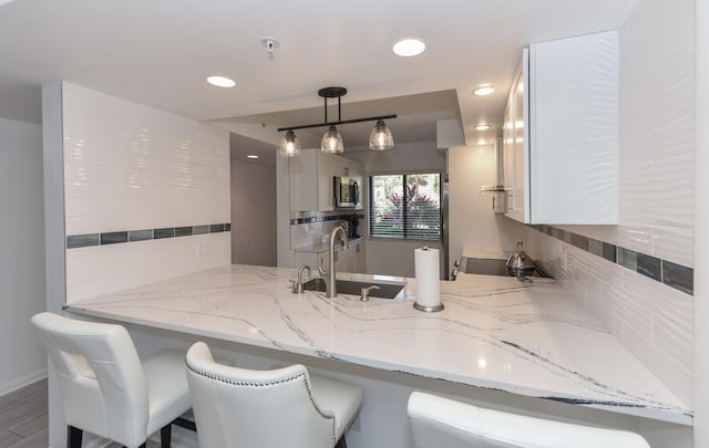 1001 Seafarer Cir Unit 102, Jupiter, FL 33477 - kitchen featuring stainless steel microwave, a sink, a peninsula, backsplash, and recessed lighting