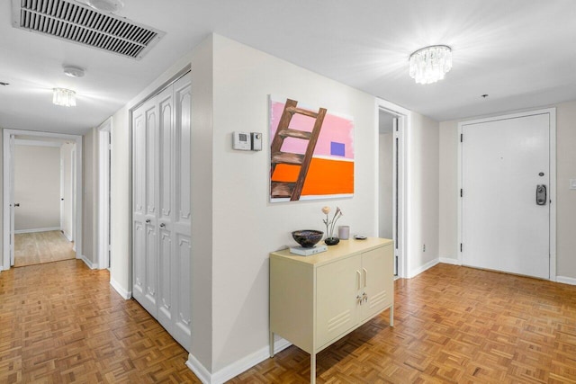 hall featuring an inviting chandelier, baseboards, and visible vents