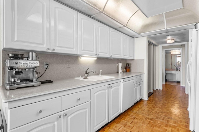 kitchen with light countertops, decorative backsplash, white cabinetry, a sink, and white appliances