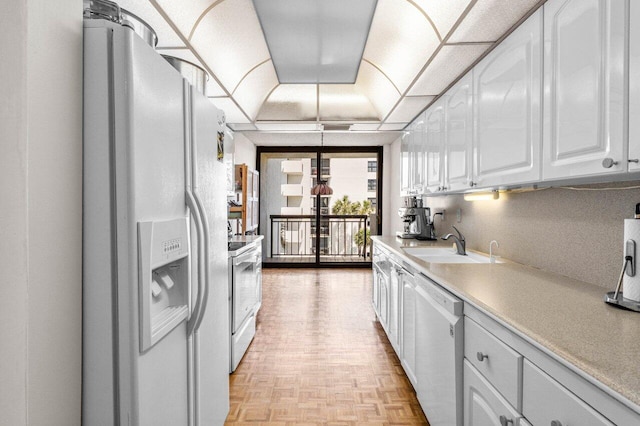 kitchen featuring light countertops, white appliances, a sink, and white cabinets