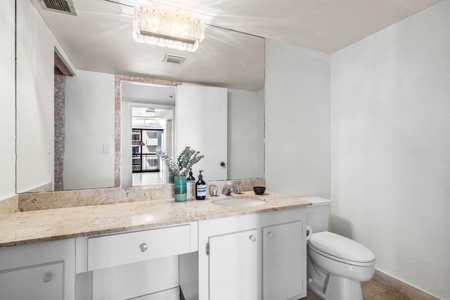 bathroom featuring toilet, vanity, and visible vents