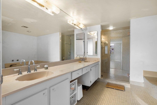 bathroom featuring double vanity, a stall shower, a sink, and tile patterned floors