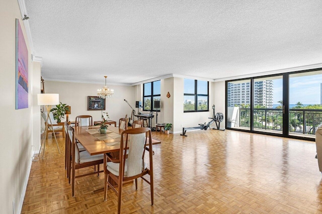 dining room featuring crown molding, a notable chandelier, a textured ceiling, a wall of windows, and baseboards