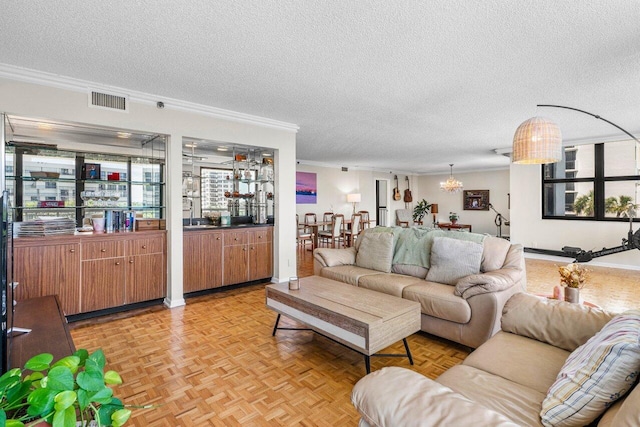 living area with an inviting chandelier, crown molding, visible vents, and a textured ceiling