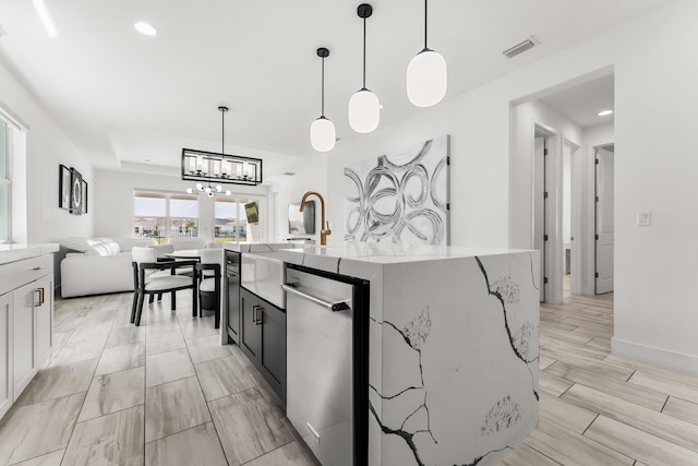 kitchen with visible vents, an island with sink, open floor plan, pendant lighting, and stainless steel dishwasher