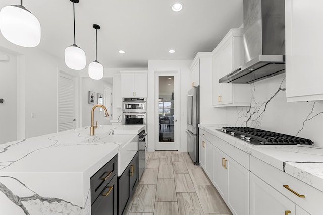 kitchen with wall chimney range hood, white cabinetry, appliances with stainless steel finishes, and decorative backsplash