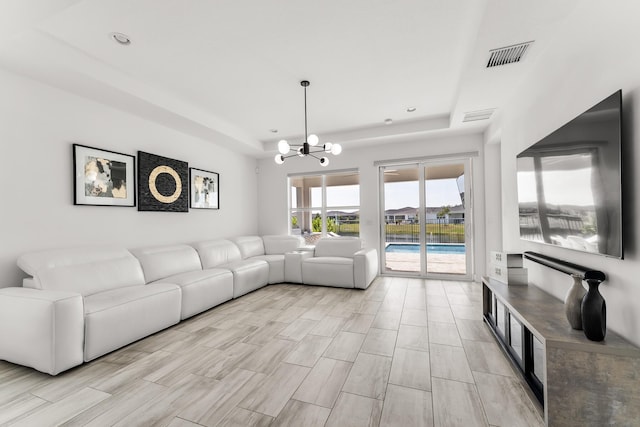 living room with a chandelier, a tray ceiling, and visible vents