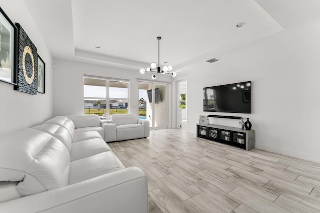 living area with a notable chandelier, visible vents, baseboards, wood tiled floor, and a tray ceiling