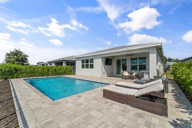 rear view of property with a patio area, ceiling fan, a fenced in pool, and stucco siding