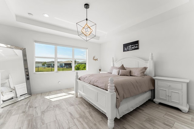 bedroom featuring light wood-style flooring, a chandelier, a raised ceiling, and recessed lighting