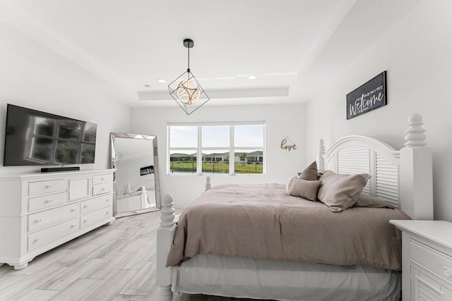 bedroom featuring light wood-type flooring, a raised ceiling, and recessed lighting