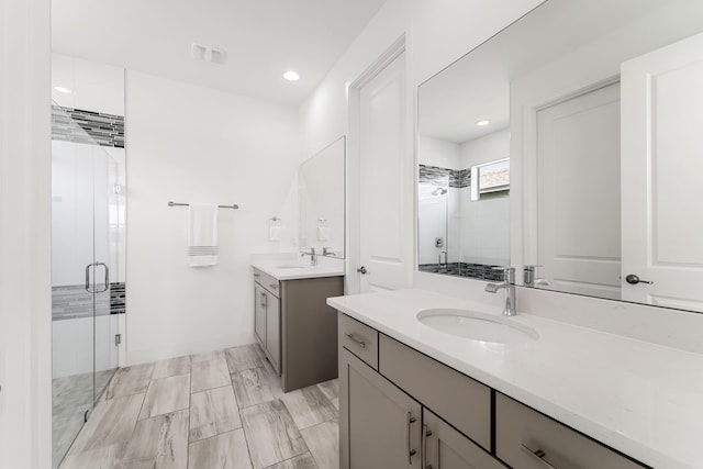 bathroom featuring a stall shower, visible vents, a sink, two vanities, and recessed lighting